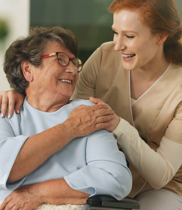 Elderly female patient is being helped by female caregiver.